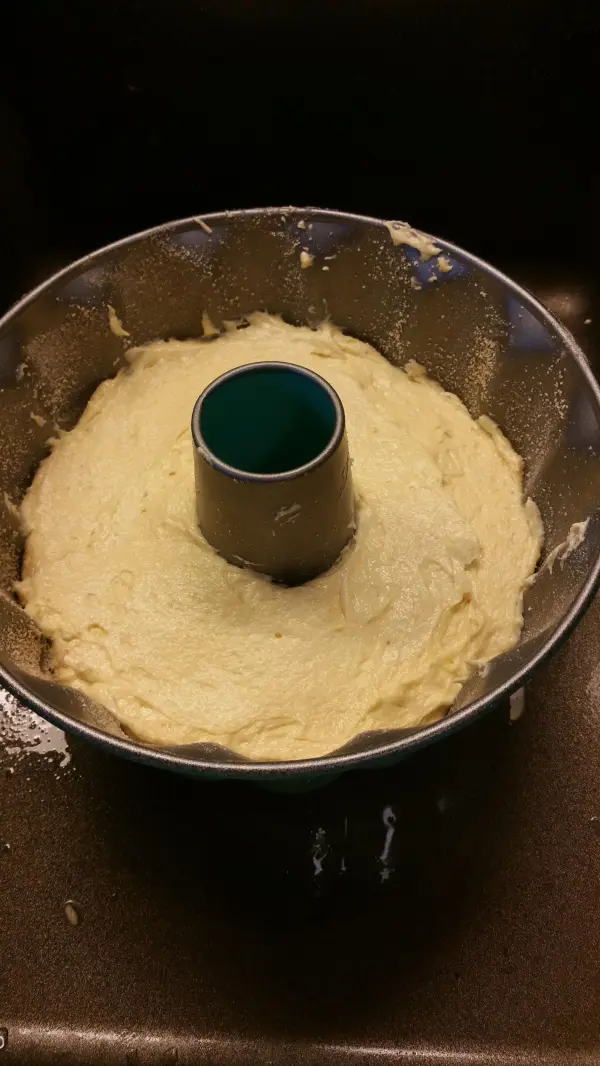 Ein Gugelhupf-Teig aus Quark füllt eine Gugelhupfform und wartet darauf, im Ofen zu backen, um seine Form zu bekommen.