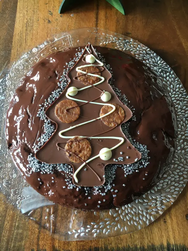 Eine festliche Schokotorte in Form eines Weihnachtsbaums ist mit Glitzer, Schokolade und Dekorationen verziert.