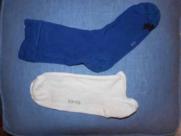 Ein blauer und ein weißer Socken liegen auf einem blauen Stoff. Die Socken könnten für DIY-Putzlappen aus alten T-Shirts verwendet werden.