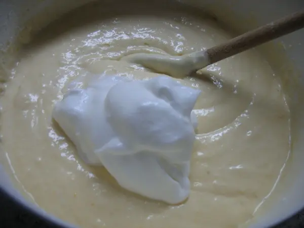 Ein cremiger Schlagsahnehäubchen wird in einen hellen, luftigen Zitronenteig eingerührt, um eine saftige Torte vorzubereiten.