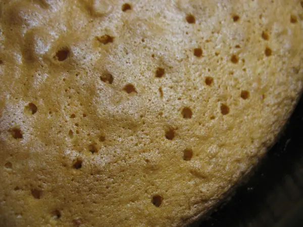 Die saftige Zitronentorte wird aus dem Ofen genommen und zeigt eine goldene Oberfläche mit kleinen Luftbläschen.