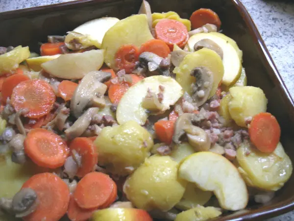 Ein Auflauf aus Kartoffeln, Äpfeln und Karotten, gemischt mit Katenschinken, garniert und frisch aus dem Ofen.