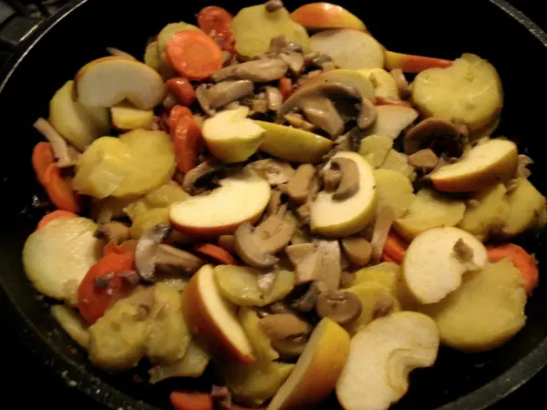 Ein bunter Kartoffel-Apfel-Auflauf mit Katenschinken, gekochte Zutaten harmonisch im Topf arrangiert.