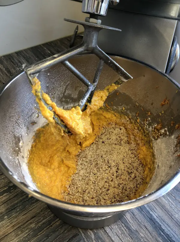 Ein silberner Rührschüssel enthält den Teig für einen saftigen Karottenkuchen, der gerade gerührt wird.