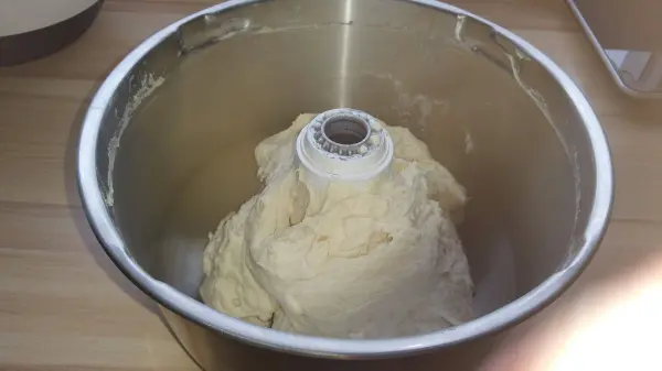 In einer Rührschüssel befindet sich ein Teig aus Weizen, der gerade geknetet wird, um knusprige Weizenbrötchen zuzubereiten.
