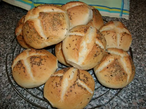 Knusprige Weizenbrötchen liegen auf einem Drahtgitter und strahlen frisch gebacken in einer hellen Küchenumgebung.