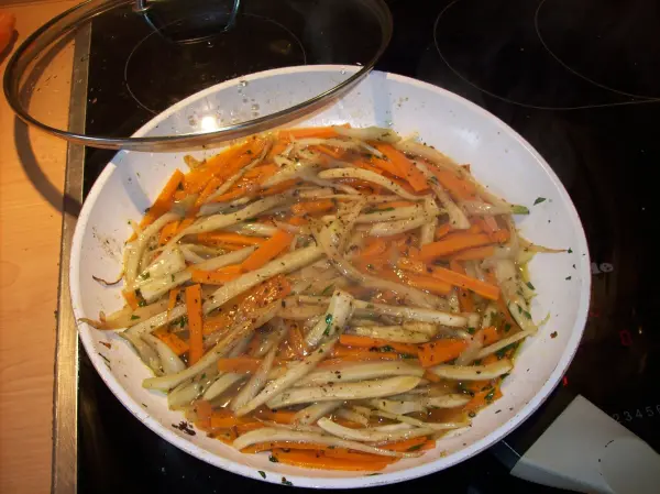 Buntes Fenchel-Möhren-Gemüse brät in einer Pfanne mit Dampf, bereit als Beilage zu einem Lachsgericht.