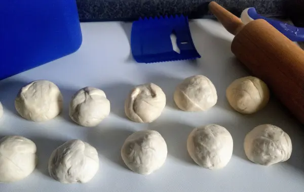 Runde Teigballen liegen auf einer Arbeitsfläche, bereit zum Ausrollen für Laugendreiecke in einer Küchenumgebung.