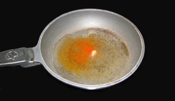 In einer Pfanne ist Öl erhitzt, mit einer leuchtend orangefarbenen Kürbisbrötchen-Masse, bereit zum Braten.