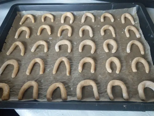 Kleine Vanillekipferl auf einem Backblech, bereit zum Backen in einer gemütlichen Küche.