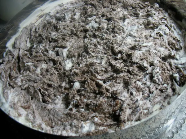 Eine Schneegestöber-Torte besteht aus unregelmäßigen Schichten von Sahne und Schokoladenstückchen in einer runden Form.