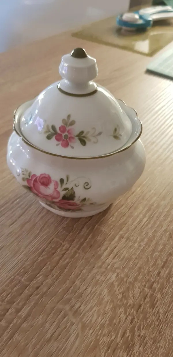 Ein geschmücktes Keramikgefäß steht auf einem Holzschreibtisch, bereit für die Verwendung als Nadelkissen.
