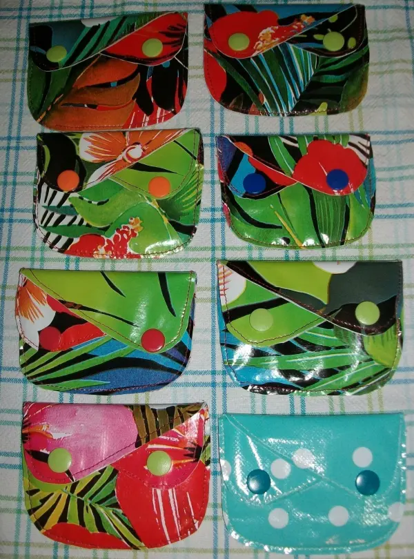 Bunte, selbst genähte Geldtaschen liegen ordentlich auf einer karierten Oberfläche und zeigen kreative Designs und Drucke.