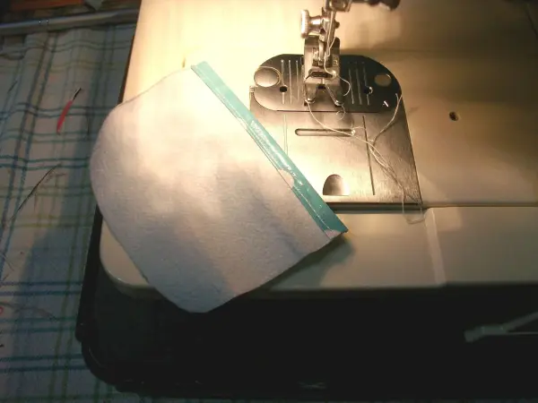 Eine weiße Stofftasche wird an einer Nähmaschine genäht, um eine kleine, einfache Geldtasche selbst zu machen.