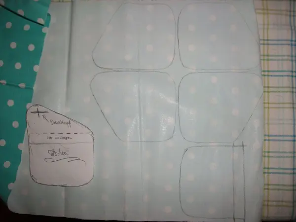Das Nähprojekt zeigt zugeschnittenes, gepunktetes Material für kleine Geldtaschen auf einem karierten Untergrund.