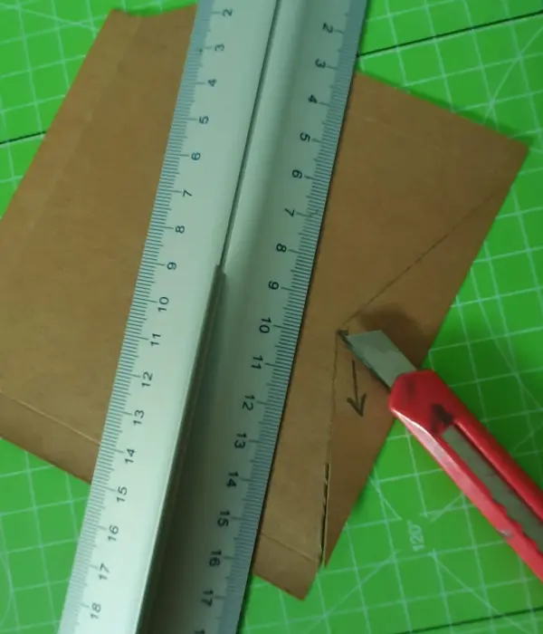 Ein Cutter schneidet eine braune Karte mit einem Lineal auf einer grünen Schneidematte, während eine Karte für die Versetzung entsteht.