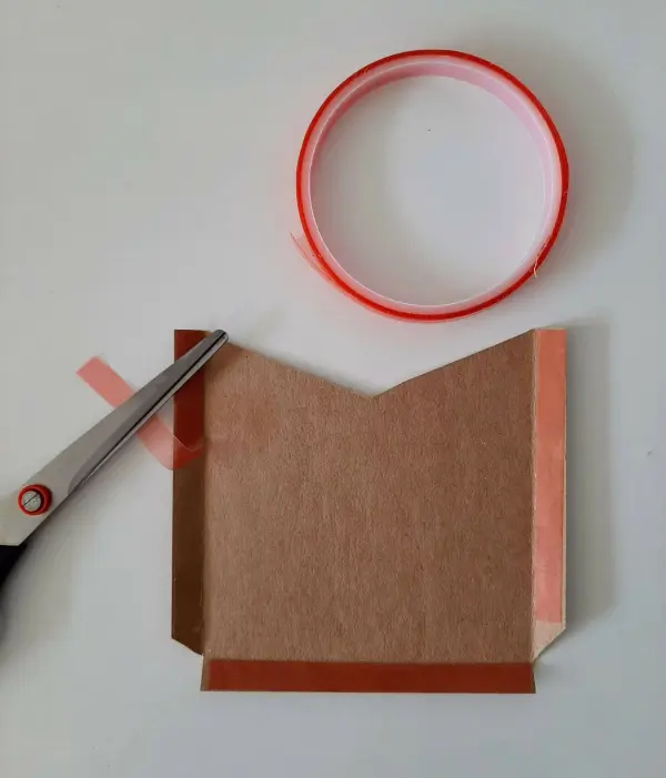 Eine haushaltsübliche Schere schneidet braunes Papier, um eine Glückwunschkarte zur Versetzung in die nächste Klasse zu gestalten.