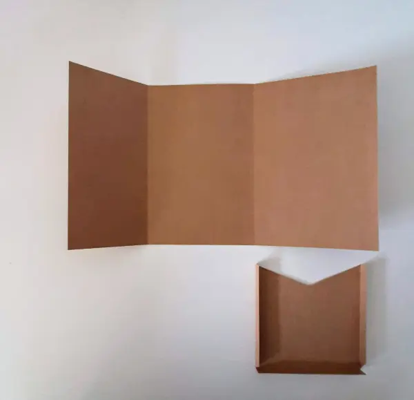 Eine leere, braune Glückwunschkarte zur Versetzung liegt offen auf einem Tisch, bereit zum Beschriften.