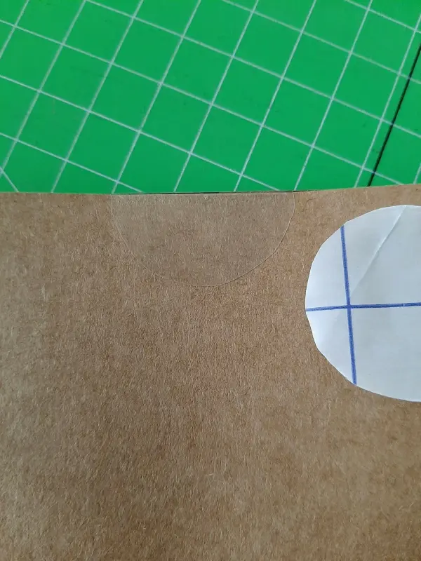 Eine braune Glückwunschkarte mit einem Aufkleber liegt auf einem grünen, karierten Untergrund.