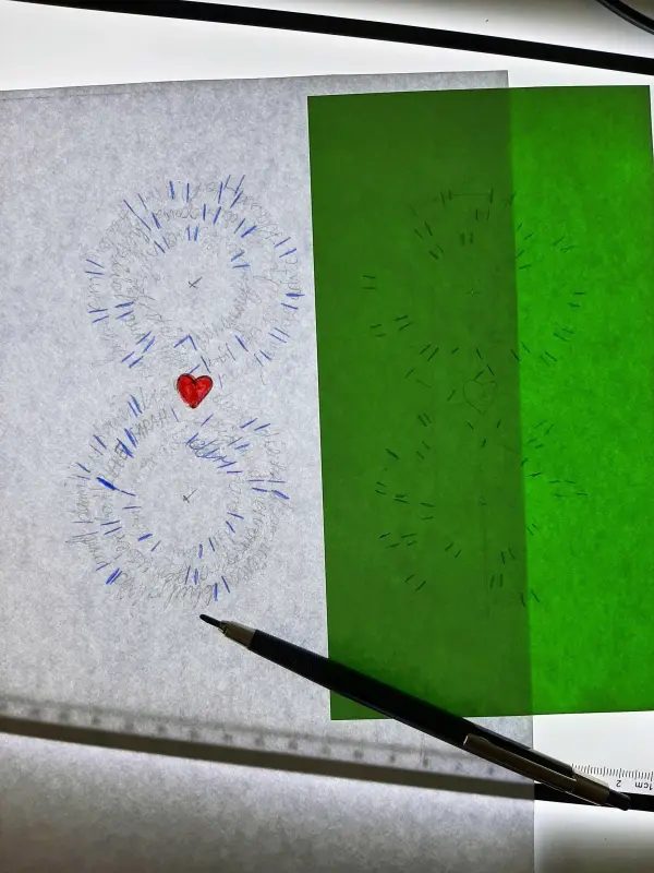 Auf einem Tisch liegt eine handgemachte Glückwunschkarte mit bunten Zeichnungen und einem roten Herz in der Mitte.