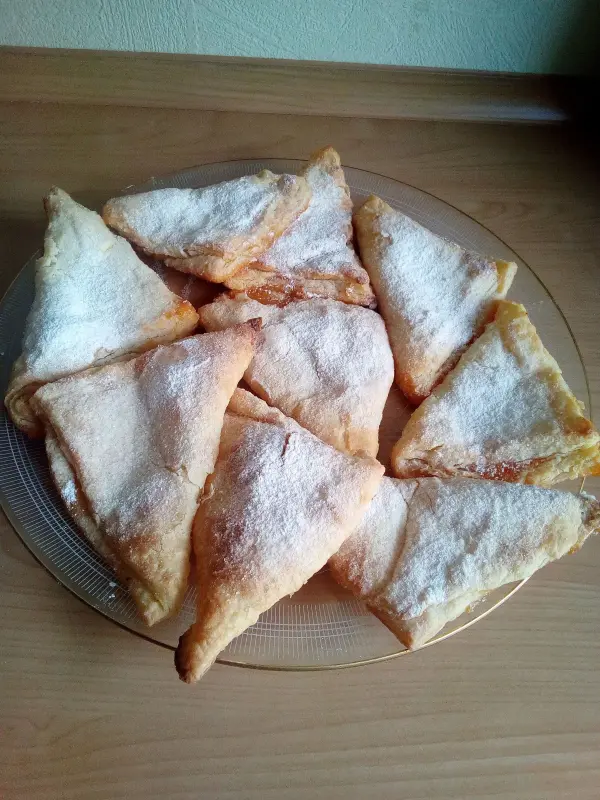 Quark-Kissen liegen auf einem Teller, puderzuckerbestäubt, bereit zum Genießen in einer gemütlichen Küche.