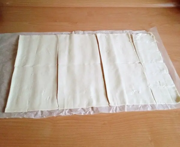 Blätterteig ist gleichmäßig ausgerollt und auf Backpapier platziert, bereit zur Zubereitung von süßen Quark-Teilchen.