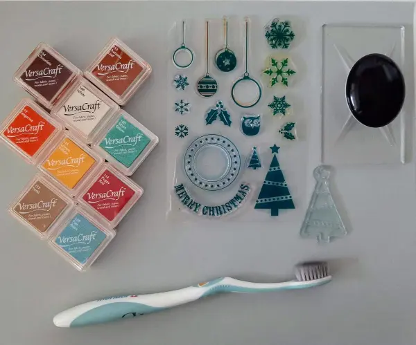 Bunte Stempelkissen und Weihnachtsstempel liegen bereit, um eine kreative Weihnachtskarte mit einem gefalteten Tannenbaum zu gestalten.
