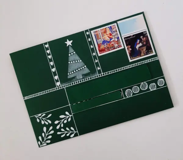 Eine grüne Weihnachtskarte zeigt einen gefalteten Tannenbaum, verziert mit Stempeln und dekorativen Mustern.