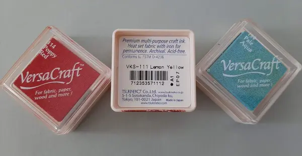 Eine rote und eine blaue Stempelkissenbox sind auf einer neutralen Oberfläche angeordnet. Sie sind für kreative Projekte konzipiert.