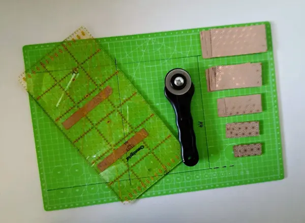 Ein grüner Schneideunterlage zeigt ein Schneidewerkzeug und gestanzte Papiere, bereit für die Gestaltung einer Weihnachtskarte.