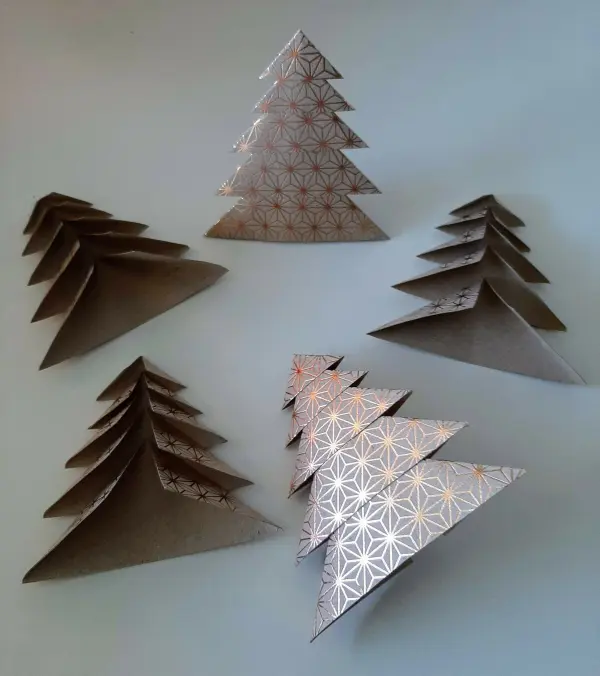Gefaltete Tannenbäume in unterschiedlichen Größen stehen auf einem hellen Untergrund und verleihen der Weihnachtskarte festlichen Glanz.