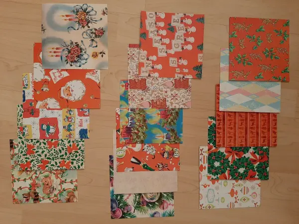 Bunte Papierrollen liegen geordnet auf einem hellen Tisch, bereit zum Basteln eines Weihnachtskranzes aus dekorativen Motiven.
