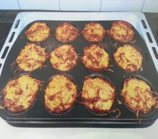 Rösti-Muffins befinden sich auf einem Blech und sind goldbraun gebacken, bereit zum Servieren in einer modernen Küche.