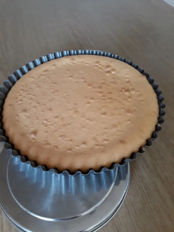 Ein Dinkelboden für Erdbeerkuchen wird auf einer silbernen Tortenplatte präsentiert, bereit zum Weiterverarbeiten.