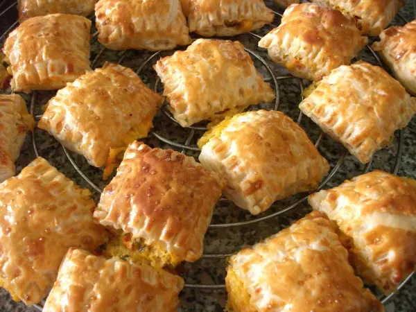 Goldene Blätterteigtaschen liegen auf einem Gitter, dampfend und lecker gefüllt, bereit zum Servieren.