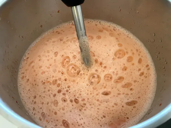 Ein Mixer rührt frischen, schaumigen Erdbeer-Limes in einem metallischen Topf, bereit für die Grillparty.