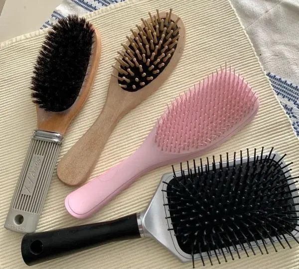 Haarbürsten liegen auf einem hellen Untergrund und sind bereit zur Reinigung mit Spülmittel und Backpulver.