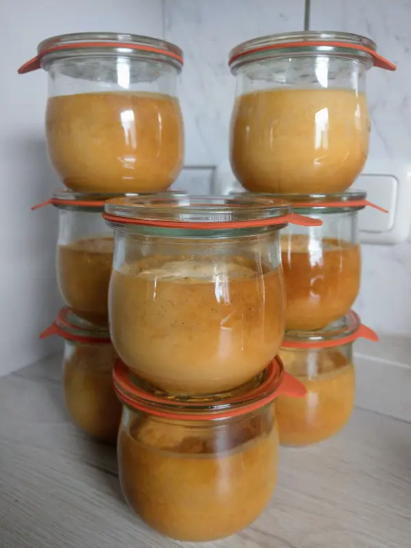 Leckere Käsekuchen im Glas stehen stapelweise auf einem hellen Tisch, bereit zum Genießen oder Einmachen.