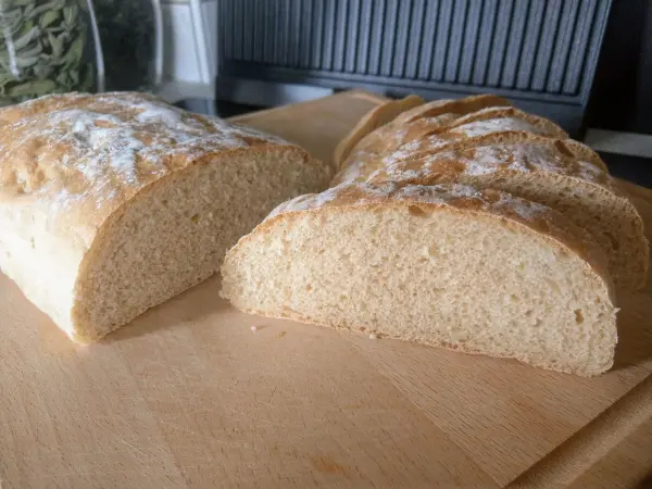 Das frisch gebackene Dinkel-Ciabatta liegt auf einem Holzbrett, in dünne Scheiben geschnitten, mit einer goldenen Kruste.