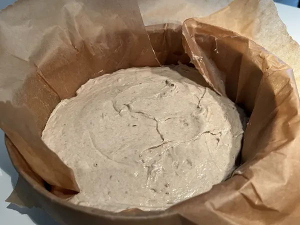 Ein runder Behälter mit einem glatten, fermentierten Teig für Roggenvollkorn-Sauerteigbrot, vorbereitet zum Backen.