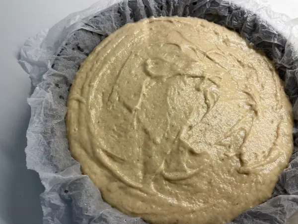 Ein cremiger Apfel-Joghurt-Kuchen-Mix liegt in einer Backform, bereit zum Backen in einer modernen Küche.