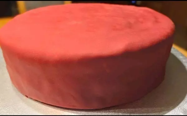 Roten Fondant weichkneten, ausrollen und anschließend den Kuchen damit eindecken.