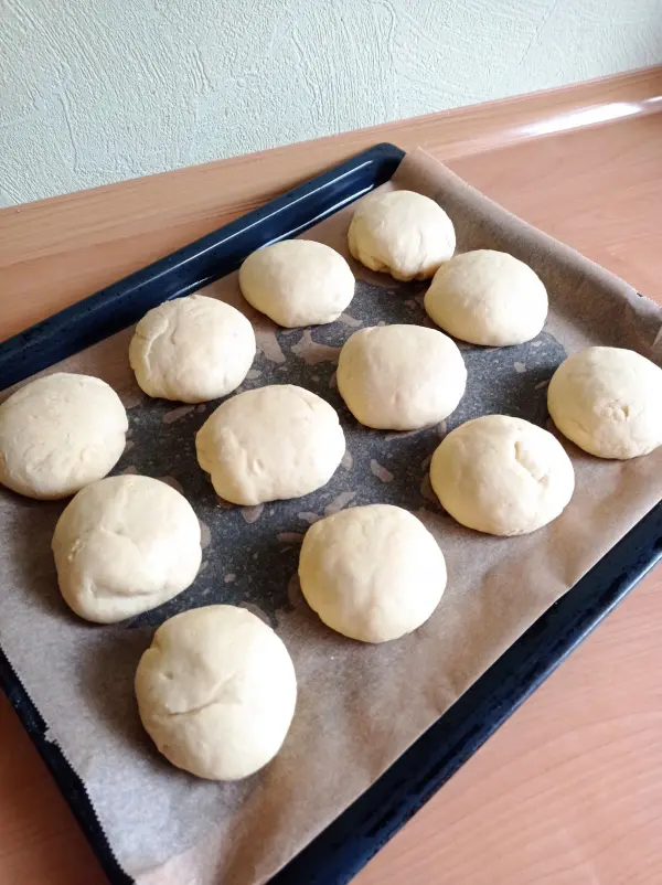 Runde Teiglinge liegen auf einem Backblech und warten darauf, im Ofen zu backen, um frische Berliner zu werden.