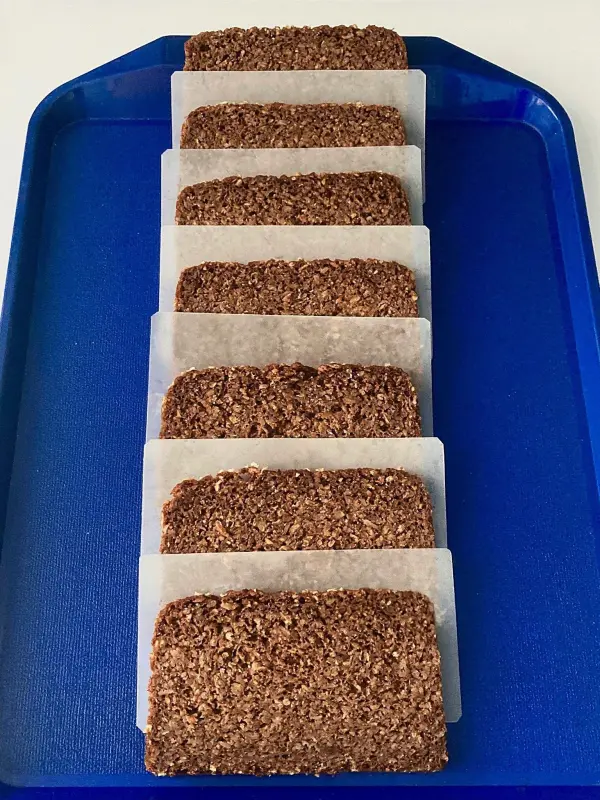 In auf Papier eingewickeltes Brot liegt ordentlich auf einem blauen Tablett, bereit zum Einfrieren.