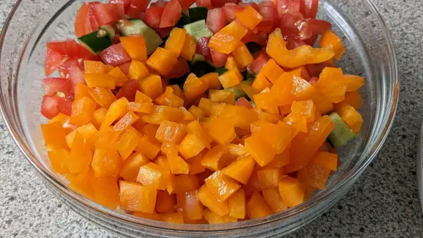 Bunte, gewürfelte Paprika und Tomaten liegen in einer Schüssel, bereit zur Zubereitung von Türkischem Bulgursalat (Kisir) mit Ajvar.