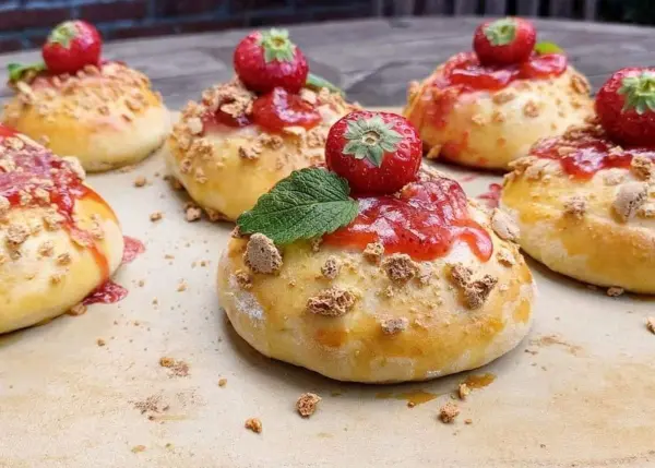 Saftige Erdbeer-Teilchen liegen verführerisch auf einem Holzbrett, dekoriert mit frischen Erdbeeren und Minze.