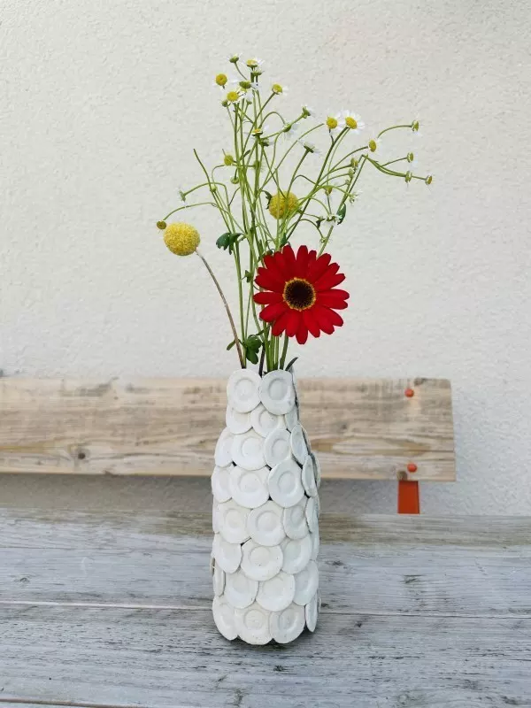 Fertige selbstgebastelte Strukturvase mit Blumenarrangement auf einem Tisch - einzigartiges Upcycling-Projekt.