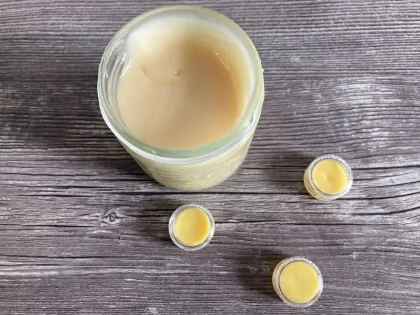 Ein Glas mit selbstgemachtem Lippenbalsam und kleinen Dosen auf einem Holzuntergrund, bereit zur Verwendung.