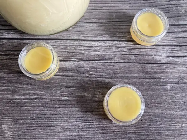 Transparente Döschen mit selbstgemachtem Lippenbalsam aus Honig stehen auf einer Holzoberfläche.