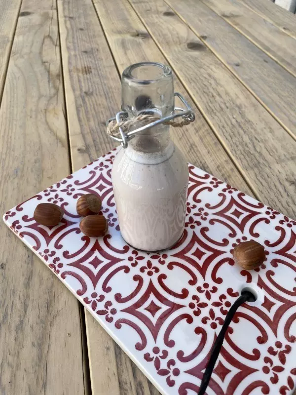 DIY Haselnussmilch: Leckeres selbstgemachtes Ergebnis in einer Glasflasche abgefüllt.